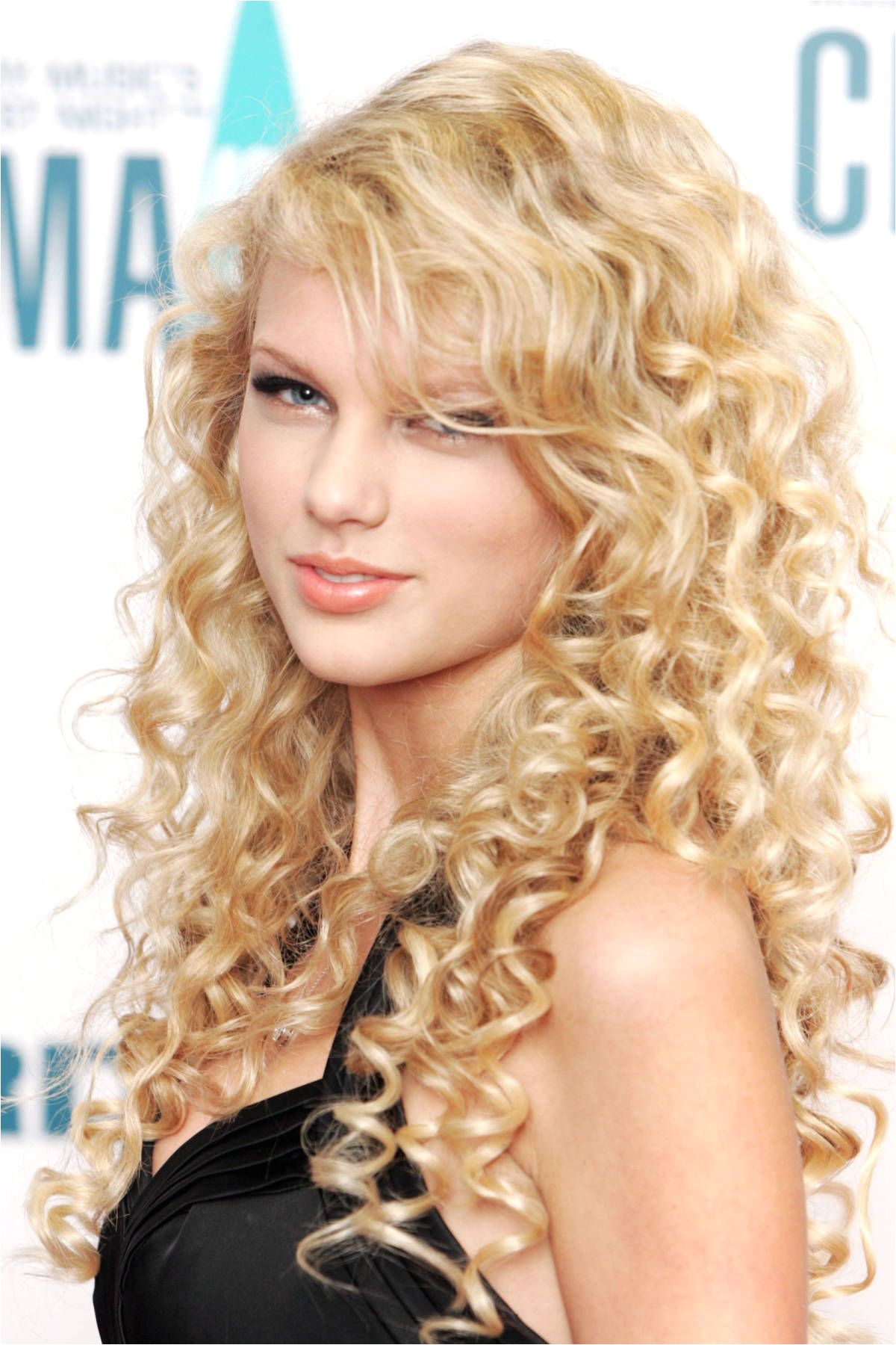 A young Taylor Swift in tight tendrils at the 40th Annual CMA Awards HarpersBAZAAR