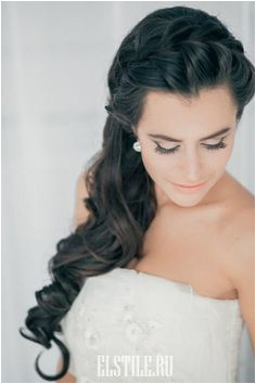 A long tousled hairstyle with a braided crown and a side swept gathering of romantic