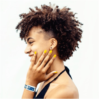 Model with curly spiral hair and bright yellow nail polish