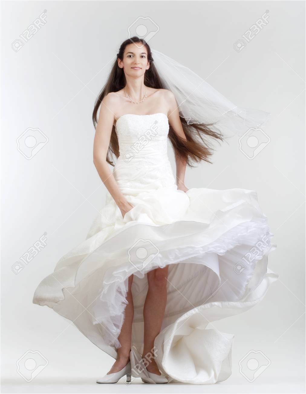 portrait od a bride with long dark hair in wedding dress isolated on gray Stock