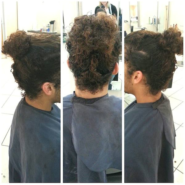 A picture of a curly haired guy ting a haircut for his curly manbun hairstyle at