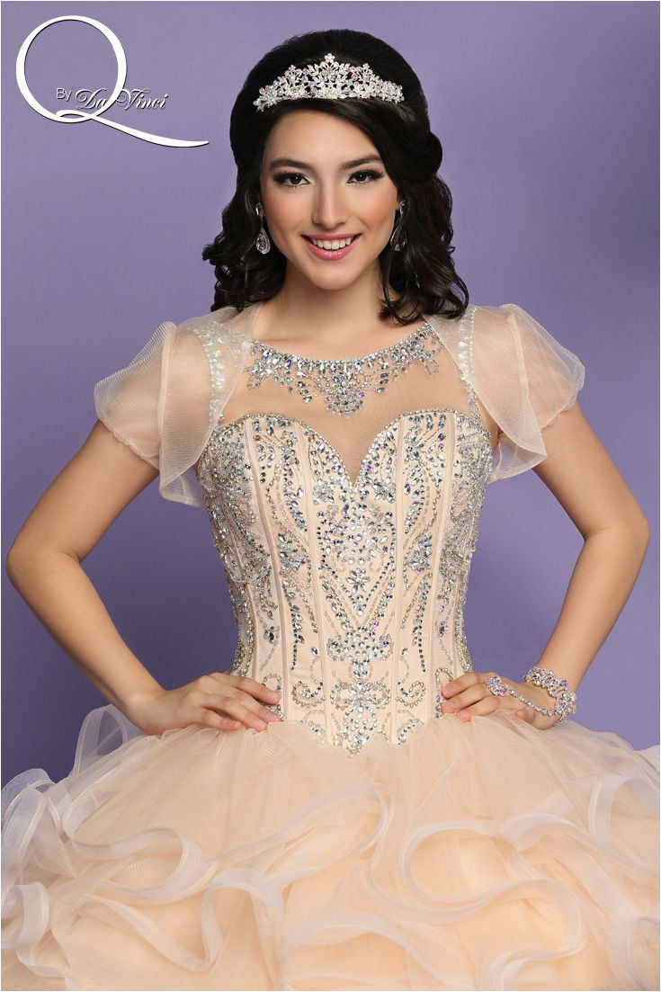 Q by DaVinci Style This elegant gown features a bateau neckline with intricate beads throughout the corset style bodice extending into a lace up