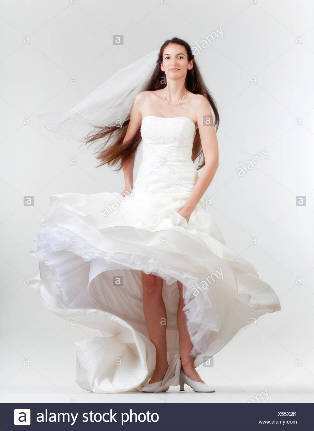 portrait od a bride with long dark hair in wedding dress isolated on gray